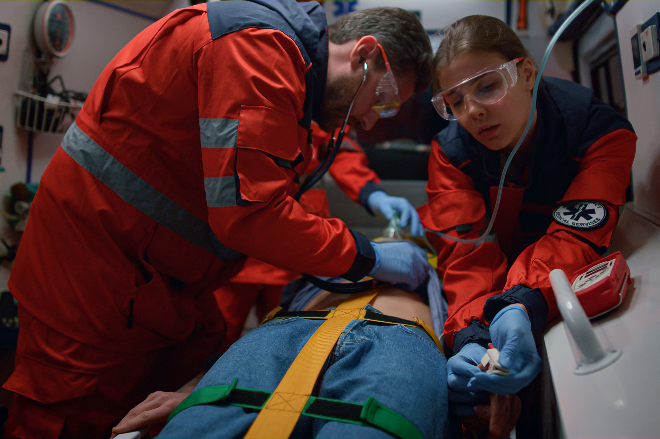 doctors providing medical help of patient in ambulance car. Professional paramedic examining patient with stethoscope. Nurse measuring oxygen saturation blood level of man with oximeter