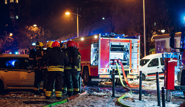 Firemen near their truck on the street having rest after they put out a fire at night. Emergency , danger, service concept. Firemen at work.